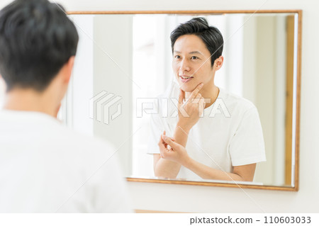 A middle-aged man checks for rough skin after wearing a mask. 110603033