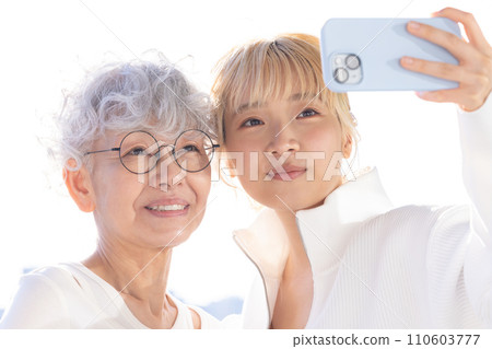 家庭：年輕女子和老年婦女用智慧型手機自拍 110603777