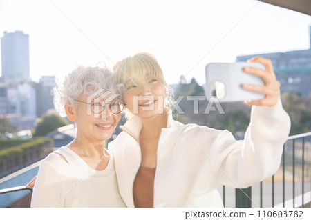 家庭：年輕女子和老年婦女用智慧型手機自拍 110603782