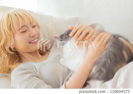 Japanese woman lying on the sofa and holding a cat 110604575