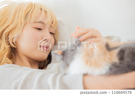 Japanese woman lying on the sofa and holding a cat 110604576