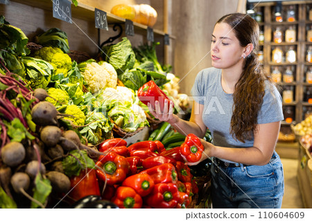 Joyful woman chooses green and red bell peppers Joyful woman chooses green and red bell peppers 110604609