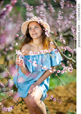 Lovely girl in hat and blue dress in peach garden 110604610