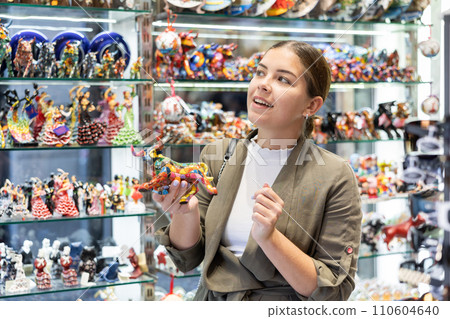 Young woman looking at bull figurine at souvenir market Young woman looking at bull figurine at souvenir market 110604640