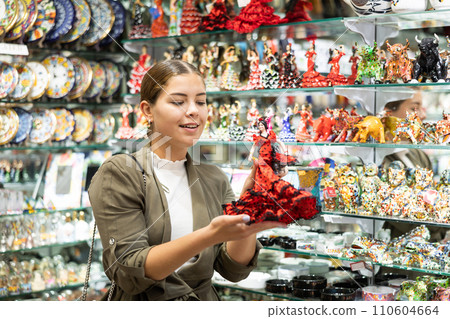Young woman looks at figurine of Spanish dancer 110604664