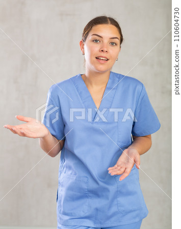 Young happy female nurse showing somewhere with her hands 110604730