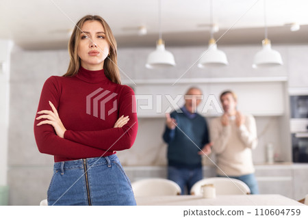 Sad woman not talking after disagreement with father and husband standing behind 110604759