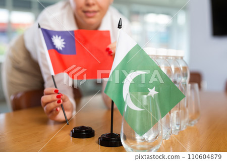 Little flag of Pakistan on table and flag of Taiwan put next to it by young woman 110604879