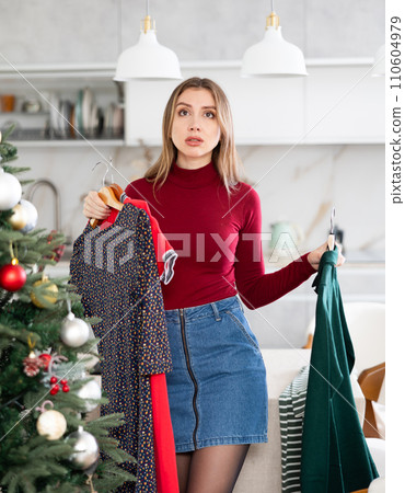 Upset indecisive woman can choose dress in her wardrobe for Christmas celebration Upset indecisive woman can choose dress in her wardrobe for Christmas celebration 110604979