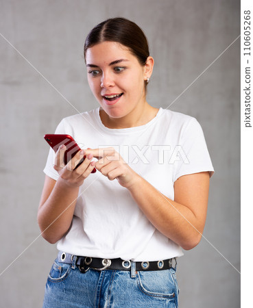 Surprised young woman reading message on phone 110605268