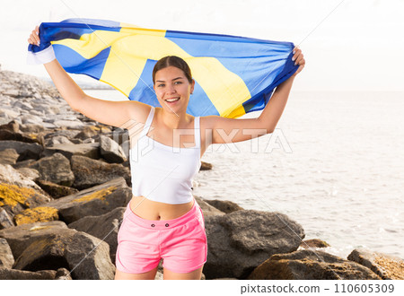 Young woman on coast posing with flag of Sweden Young woman on coast posing with flag of Sweden 110605309