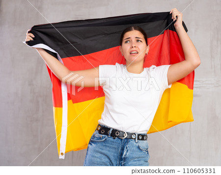 Unhappy female Germany team fan holding national flag Unhappy female Germany team fan holding national flag 110605331