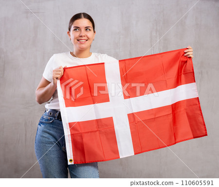 Smiling young woman holding Denmark flag Smiling young woman holding Denmark flag 110605591
