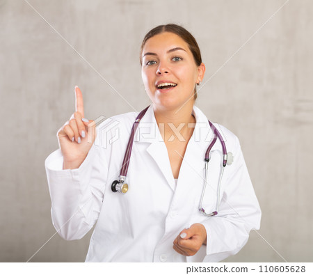 Happy young female doctor pointing to side with her finger 110605628