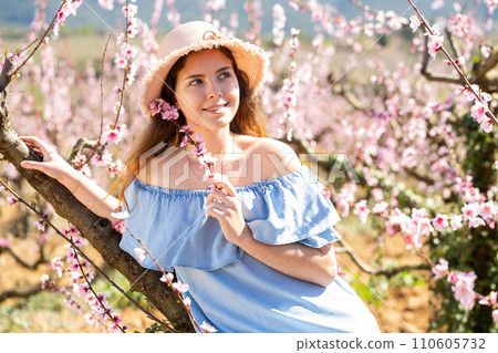 Beautiful blonde girl with long hair in a pink dress in blooming garden. Beautiful blonde girl with long hair in a pink dress in blooming garden. 110605732