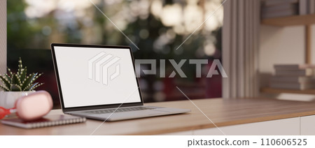 Close-up image of a white-screen laptop computer and accessories on a wooden desk in a modern room. Close-up image of a white-screen laptop computer and accessories on a wooden desk in a modern room. 110606525