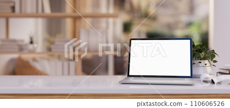 Close-up image of a white-screen laptop computer and accessories on a wooden desk in a modern room. Close-up image of a white-screen laptop computer and accessories on a wooden desk in a modern room. 110606526