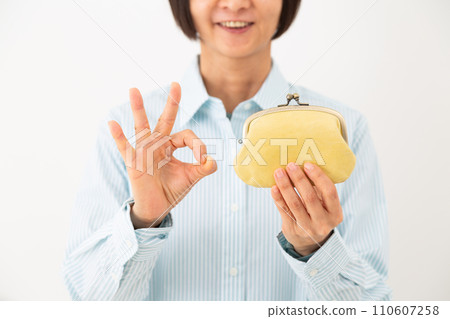 一名中年婦女的手拿著錢包,做一個圓圈標誌 一名中年婦女的手拿著錢包,做一個圓圈標誌 110607258