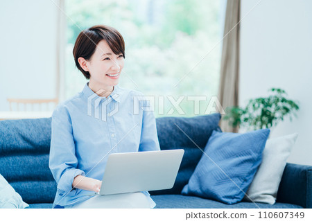 A middle-aged woman who operates a laptop in the living room. 110607349