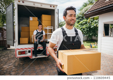 Young delivery men unload boxes outdoors. Movers cooperate in relocation service. Teamwork among colleagues. Smiling workers carrying boxes. relocation cooperation Moving Day 110609445