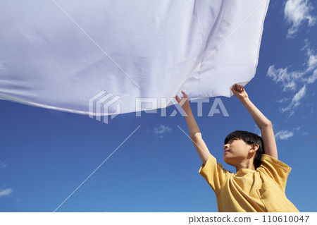 Elementary school boy spreading laundry sheets under the blue sky Elementary school boy spreading laundry sheets under the blue sky 110610047
