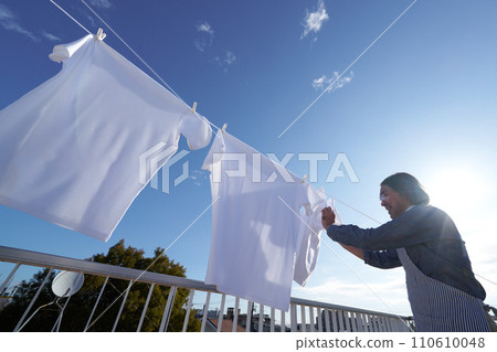 藍天下,一名男子將洗好的衣服掛在繩子上晾乾 藍天下,一名男子將洗好的衣服掛在繩子上晾乾 110610048