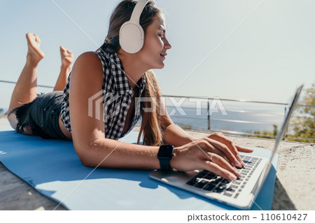 Woman laptop sea. Working remotely on seashore. Happy successful woman female freelancer working on laptop by the sea at sunset, makes a business transaction online. Freelance, remote work on vacation Woman laptop sea. Working remotely on seashore. Happy successful woman female freelancer working on laptop by the sea at sunset, makes a business transaction online. Freelance, remote work on vacation 110610427