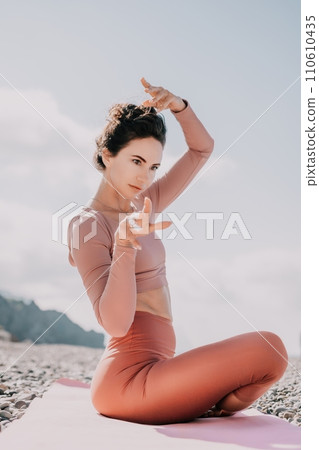 Middle aged well looking woman with black hair, fitness instructor in leggings and tops doing stretching and pilates on yoga mat near the sea. Female fitness yoga routine concept. Healthy lifestyle Middle aged well looking woman with black hair, fitness instructor in leggings and tops doing stretching and pilates on yoga mat near the sea. Female fitness yoga routine concept. Healthy lifestyle 110610435