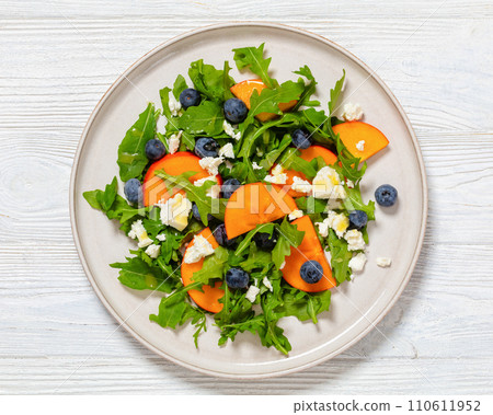 arugula persimmon cheese berries salad, top view arugula persimmon cheese berries salad, top view 110611952