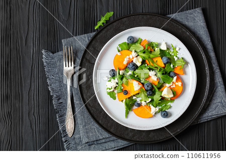 arugula persimmon cheese berries salad, top view arugula persimmon cheese berries salad, top view 110611956