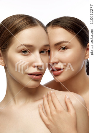 Vertical portrait of two young beautiful young Caucasian woman with clean fresh skin against white studio background. Concept of facial treatment. 110612277