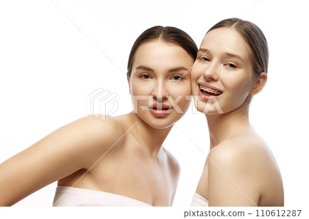 Two women with natural makeup that highlights their clear skin and delicate beauty features against white studio background. Two women with natural makeup that highlights their clear skin and delicate beauty features against white studio background. 110612287