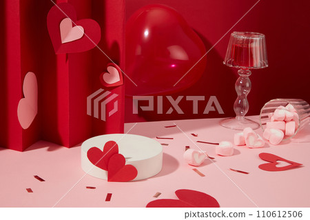 Round podium in white color displayed with red balloon, many heart-shaped marshmallows. Glamour minimal pedestal for beauty, cosmetic product presentation 110612506