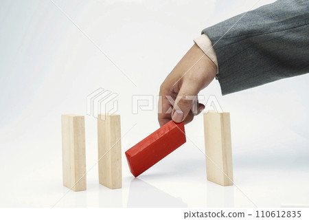 Business hand put a red wooden block in a row of brown wooden blocks Business hand put a red wooden block in a row of brown wooden blocks 110612835