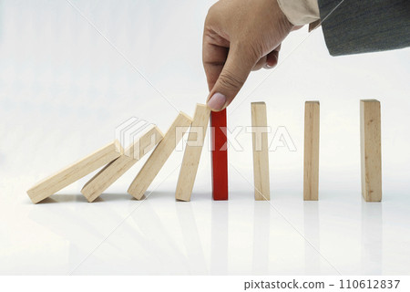 Business hand put a red wooden block into a fallen row of brown wooden blocks 110612837
