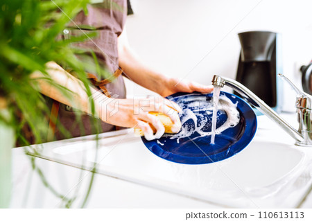 Housework washing dishes after dinner, housewife washes plate under running water Housework washing dishes after dinner, housewife washes plate under running water 110613113