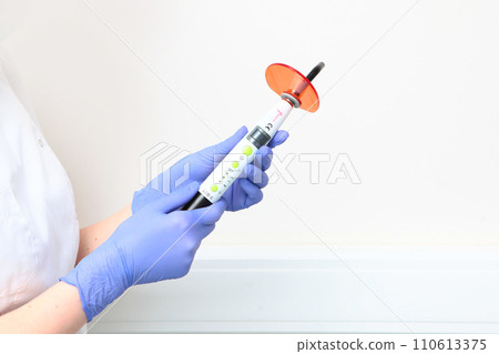 A lamp for curing light fillings in the hands of a doctor. Modern dentistry. An unrecognizable person. 110613375