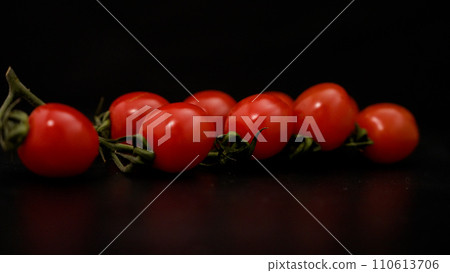 Delicious red cherry tomatoes rotate smoothly on a black wooden table close-up. Cherry tomatoes are spinning on the table. Delicious red cherry tomatoes rotate smoothly on a black wooden table close-up. Cherry tomatoes are spinning on the table. 110613706