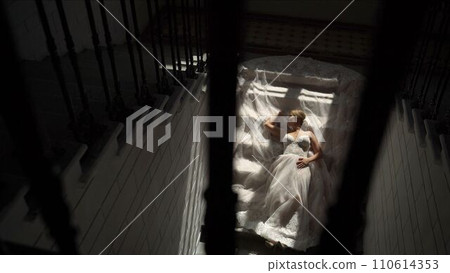 The bride lies on the stairs. Young bride in a magnificent dress is lying on the stairs. Bride in beautiful dress is lying on the stairs. Steep Bride. The bride lies on the stairs. Young bride in a magnificent dress is lying on the stairs. Bride in beautiful dress is lying on the stairs. Steep Bride. 110614353