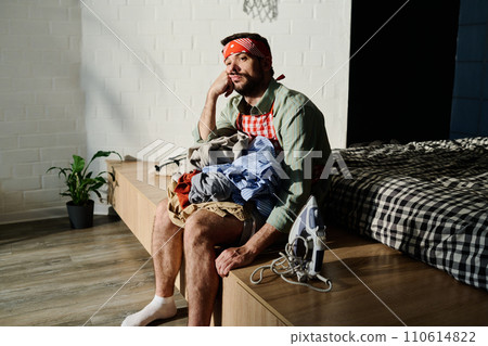 Bored young man with pile of clothes Bored young man with pile of clothes 110614822