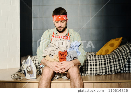 Man holding pile of crumpled clothes Man holding pile of crumpled clothes 110614826