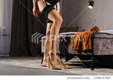 Unrecognizable woman in lingerie and stockings putting on shoes Unrecognizable woman in lingerie and stockings putting on shoes 110615700