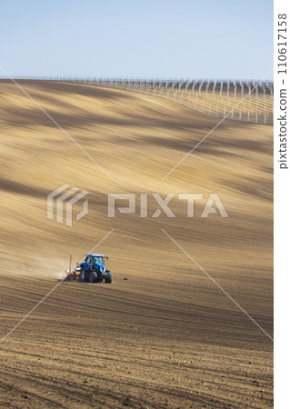 Tractor with seed drill in early spring landscape Tractor with seed drill in early spring landscape 110617158