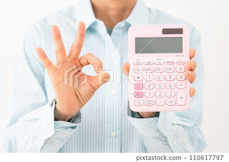 Middle-aged woman holding a calculator and making a circle sign 110617797