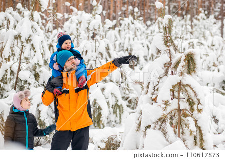 Family leisure. Father walks with his children in snowy forest on clear day. Recreation in the fresh air. 110617873