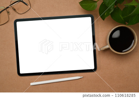 Top view digital tablet with white empty screen, coffee cup and glasses on brown background Top view digital tablet with white empty screen, coffee cup and glasses on brown background 110618285
