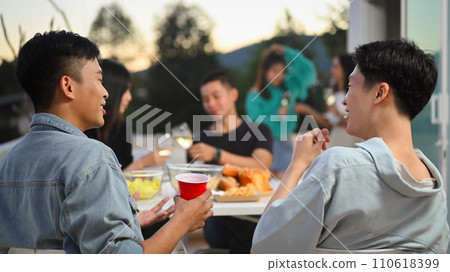 Happy friends having fun at outdoor rooftop party and chatting. Holiday celebration and friendship concept. 110618399