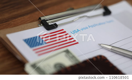 Ballpoint pen and dollar bills lying on documents for applying for visa closeup 110618501
