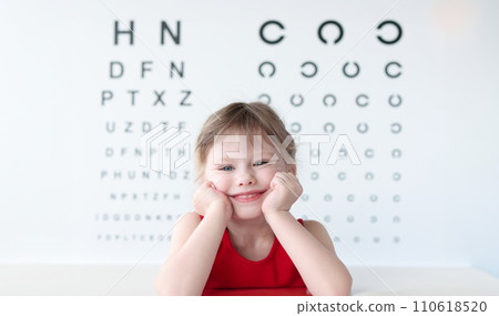 Smiling little child against vision test table in medical clinic portrait 110618520