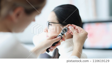 Otorhinolaryngologist examines patient ear with an otoscope 110619129
